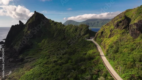 Aerial forward flight over green Orchid Island with path between mountains and blue ocean in background at sunset time photo