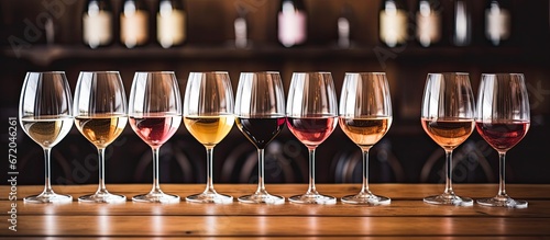 A variety of wine types arranged in tasting glasses alongside sommeliers at an indoor wooden table captured in a closeup shot