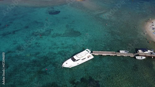 Yacht speedboat moored at beach jetty in Budikovac blue lagoon, croatia with people swimming photo