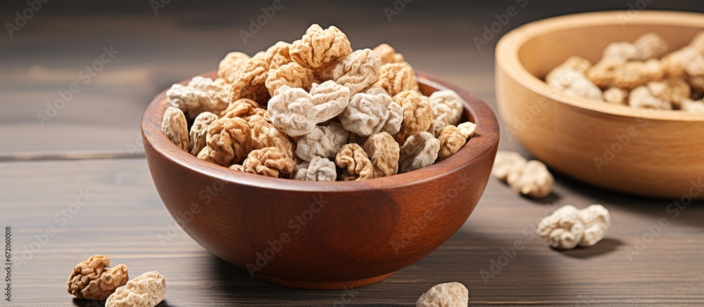 Mulberries which are white and have been dried are displayed in a wooden bowl on top of a wooden surface Mulberries which are white and have been dried are displayed in a wooden bowl on top of a wooden surface