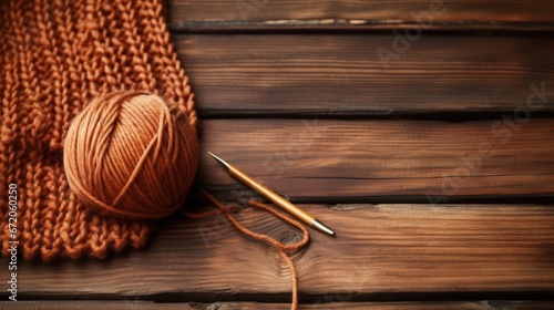 Knitting project in progress, stockinette stitch is applied. Brown cotton yarn and circular knitting needles against wooden background. Female hobby knitting. Crafting activity. Focus selection.