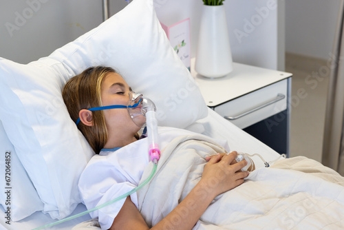 Caucasian girl patient with drip and wearing oxygen mask asleep in hospital bed photo