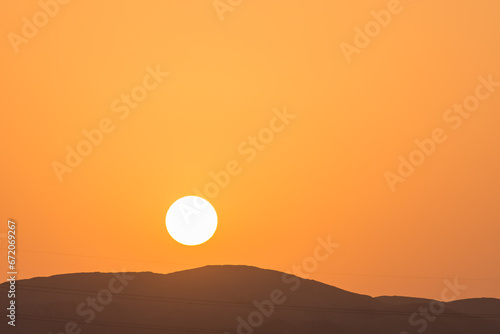 bright sun with orange sky over a black mountain on vacation