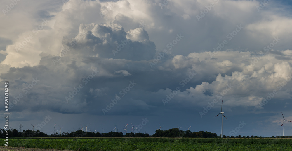 dark dense rainclouds over pinwheels on a green field panorama dark dense rainclouds over pinwheels on a green field panorama