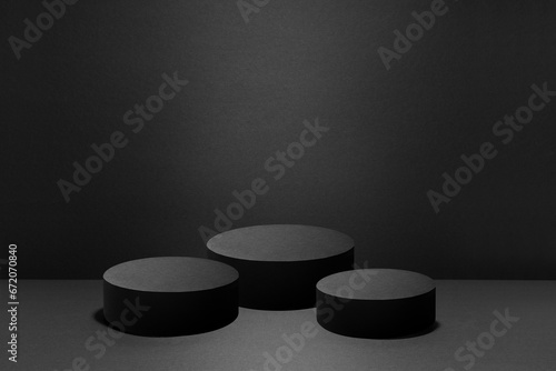 Abstract three black round podiums with light of spotlight for cosmetic products, mockup on black background. Black stage template for showing products, advertising, design, poster, text, card.