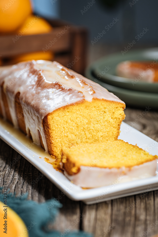 Popular biscuit dessert called Pound cake with white topping, served with oranges on rustic wooden background Popular biscuit dessert called Pound cake with white topping, served with oranges on rustic wooden background