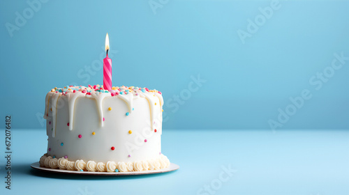 Birthday cake with burning candle on blue table and wall background  space for text. High quality photo