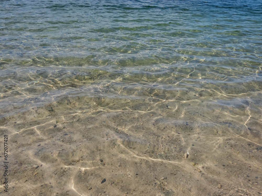Crystal clear transparent water in shades of blue and turquoise with fine white sand base with bright reflection of sun in water movement Crystal clear transparent water in shades of blue and turquoise with fine white sand base with bright reflection of sun in water movement