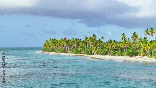 Azure Caribbean sea water on white sand and blue sky. Coconut palm trees line the shores of a beautiful sea beach. Amazing exotic seascape. Palm Island tropical background. Natural sunny dayscape. photo