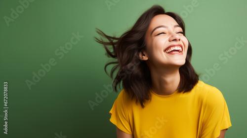 Beaming Eurasian woman in her 20s with green studio backdrop photo