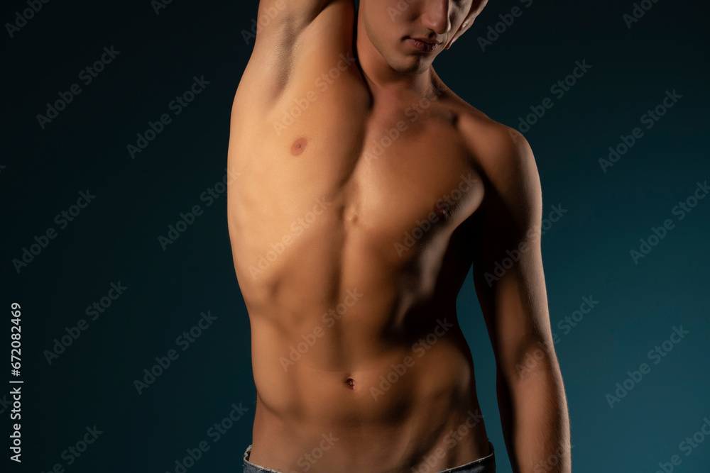 the torso of a young athletic guy. concept: the male body after exercise and diet. men's health: shaved breasts on a dark background