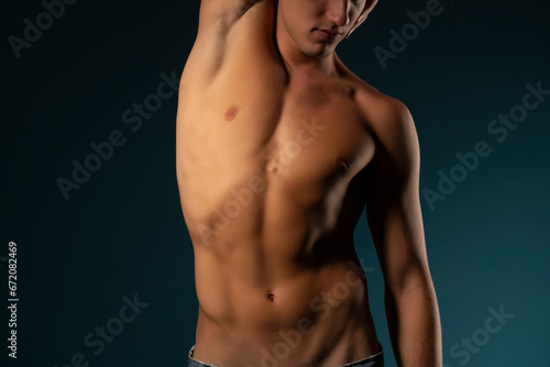 the torso of a young athletic guy. concept: the male body after exercise and diet. men's health: shaved breasts on a dark background photo