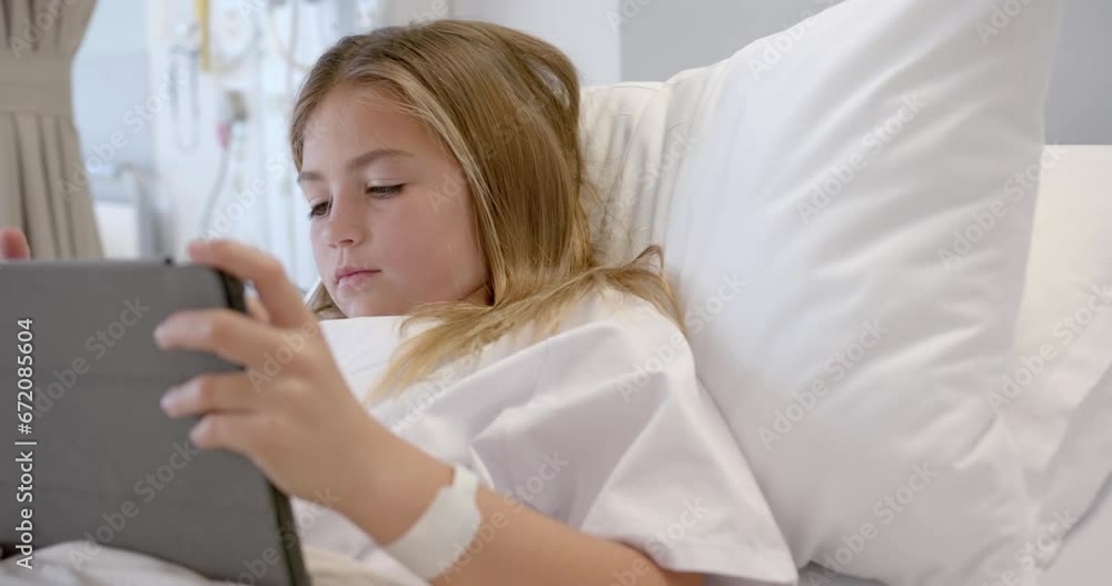 Caucasian girl patient sitting up in hospital bed using tablet, slow motion Caucasian girl patient sitting up in hospital bed using tablet, slow motion
