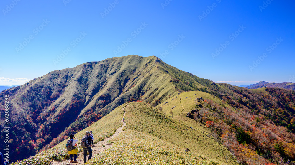 剣山の中腹から見た次郎笈の景色と稜線歩きをする登山者