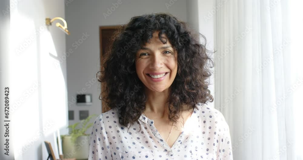 Portrait of happy biracial woman with curly hair at home, slow motion