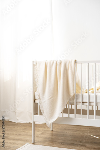 Fototapeta Naklejka Na Ścianę i Meble -  Muslin baby blanket hanging on child's bed in nursing room