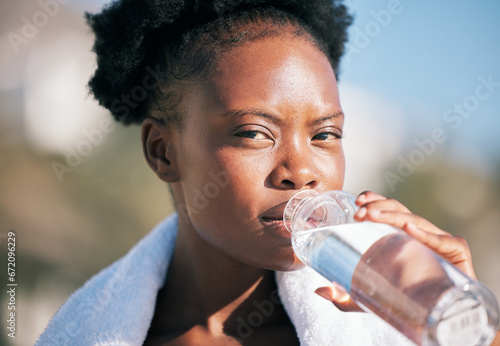 Face of black woman and drinking water for sports break, energy and workout, training and diet. Portrait of thirsty female athlete, bottle and nutrition for hydration, exercise and recovery of runner photo