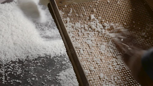 person sifting cassava flour on top of a pan to make tapioca