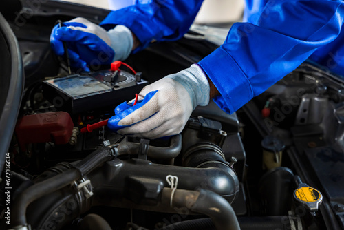 Close up car mechanic hands using tool fixing openhooded car in auto repair