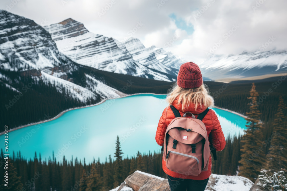 Φωτογραφία Rear view of a stylish girl, with a backpack and jacket, looking at the mountains and the lake, relaxing in the winter nature