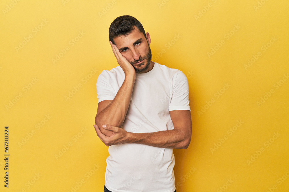 Young Hispanic man on yellow background who is bored, fatigued and need a relax day.