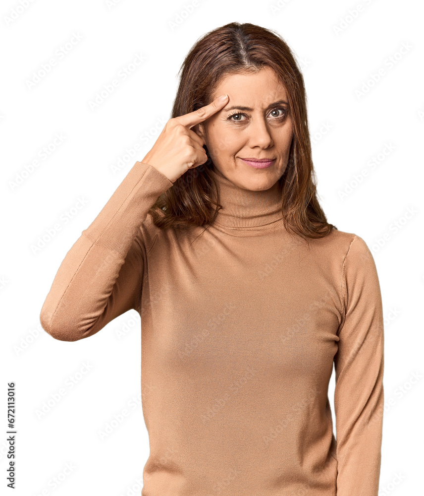 Middle-aged woman portrait in studio setting pointing temple with finger, thinking, focused on a task. Middle-aged woman portrait in studio setting pointing temple with finger, thinking, focused on a task.