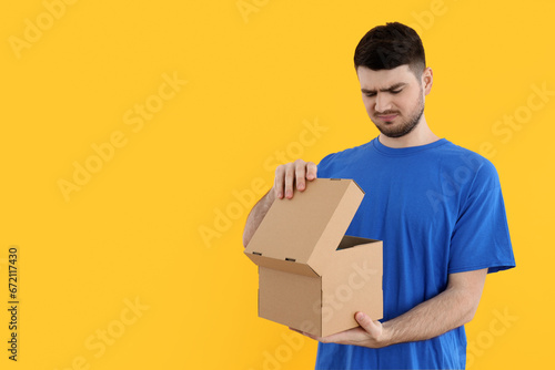 A young attractive guy is looking into a cardboard box