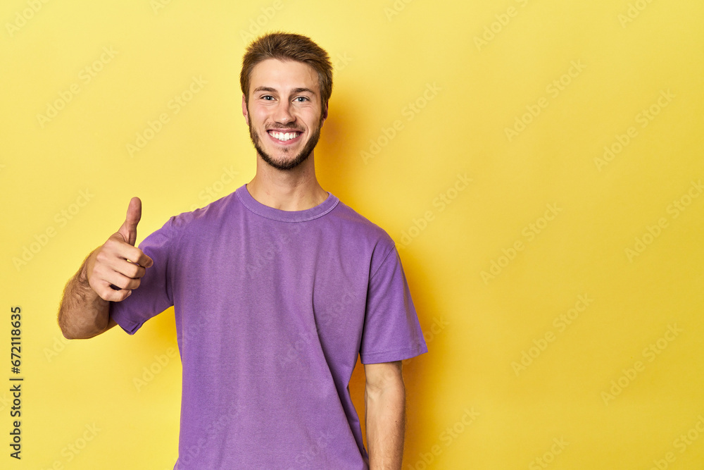 Young Caucasian man on a yellow studio background smiling and raising thumb up Young Caucasian man on a yellow studio background smiling and raising thumb up