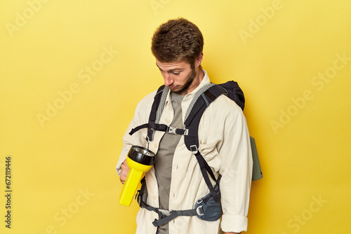 Mountain traveler with backpack and flashlight on yellow studio background