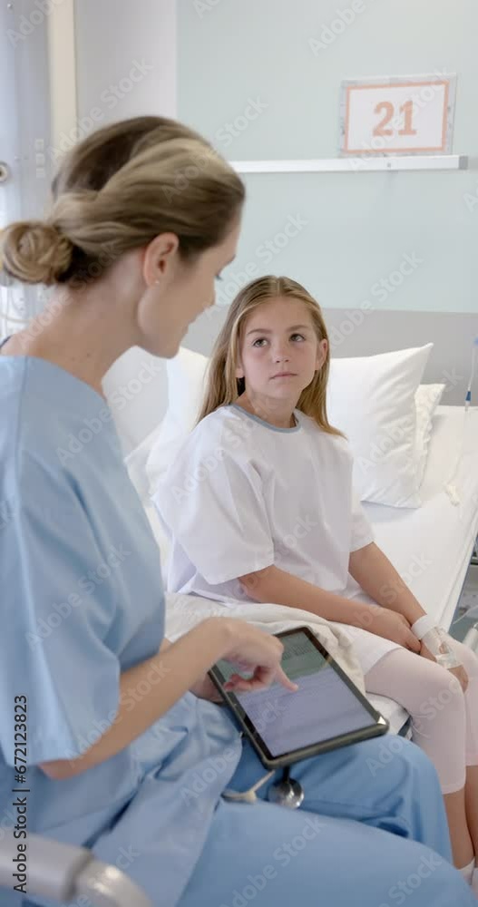 Vertical video of caucasian female doctor with tablet talking with girl patient on bed, slow motion Vertical video of caucasian female doctor with tablet talking with girl patient on bed, slow motion