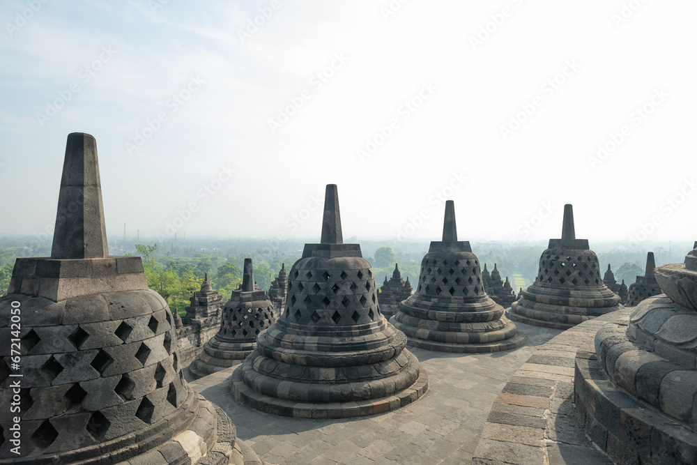 (Selective focus) Stunning view of the Borobudur bell shaped stupas during a beautiful sunrise. Borobudur is a Mahayana Buddhist temple in Magelang Regency in Central Java, Indonesia.