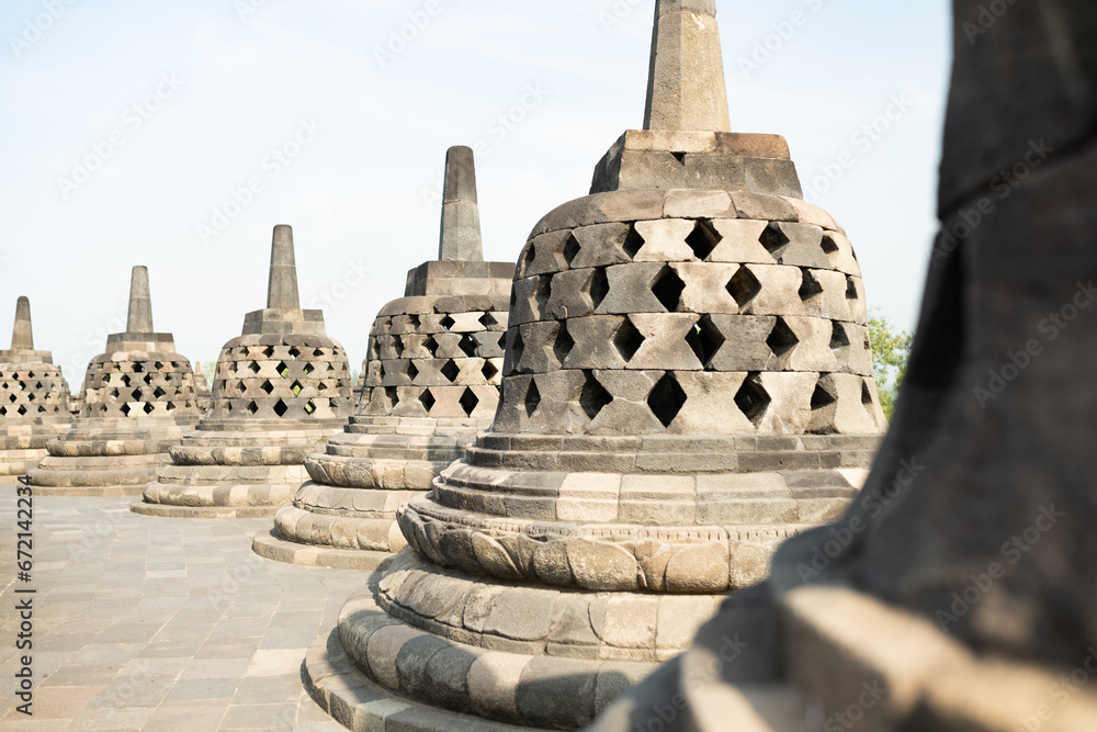 (Selective focus) Stunning view of the Borobudur bell shaped stupas during a beautiful sunrise. Borobudur is a Mahayana Buddhist temple in Magelang Regency in Central Java, Indonesia.