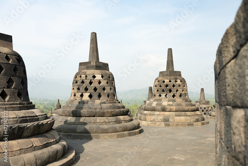 (Selective focus) Stunning view of the Borobudur bell shaped stupas during a beautiful sunrise. Borobudur is a Mahayana Buddhist temple in Magelang Regency in Central Java, Indonesia.