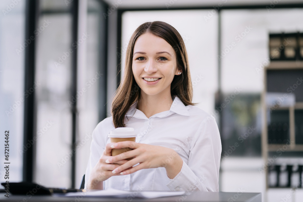 portrait of a business woman Self-confident young woman sit holding coffee mug and working laptop.  Casual business.
