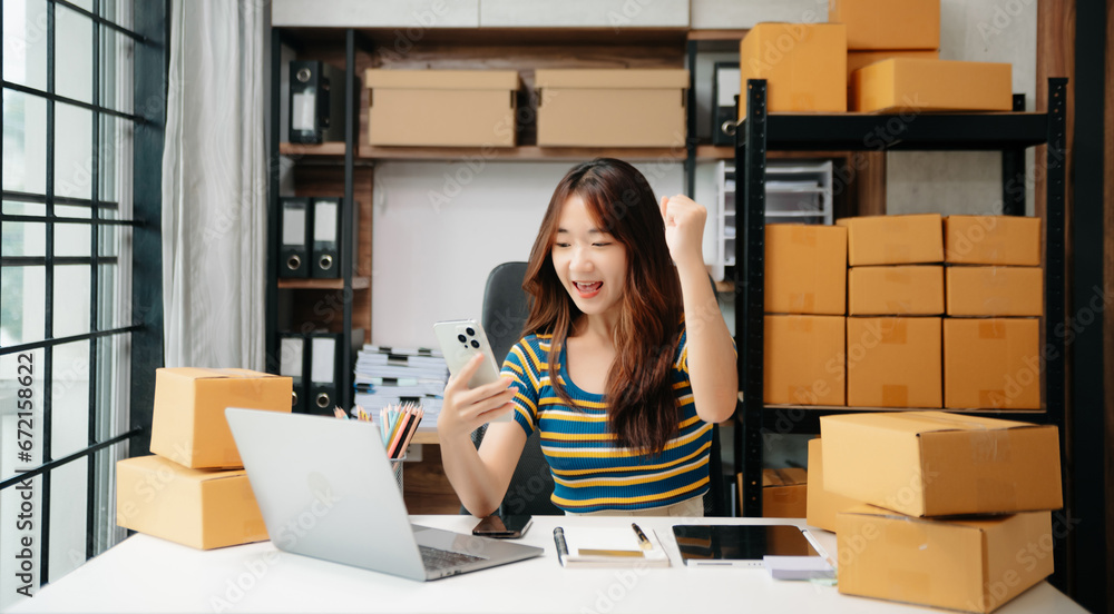 Young woman holding a smartphone, tablet showing payment success and credit card with yellow parcel box as online shopping concept Young woman holding a smartphone, tablet showing payment success and credit card with yellow parcel box as online shopping concept