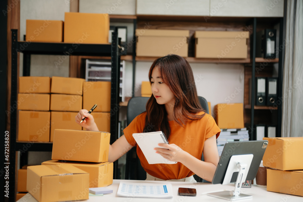 Young woman prepare parcel box and standing check online orders for deliver to customer on tablet, laptop Shopping Online concept. Young woman prepare parcel box and standing check online orders for deliver to customer on tablet, laptop Shopping Online concept.