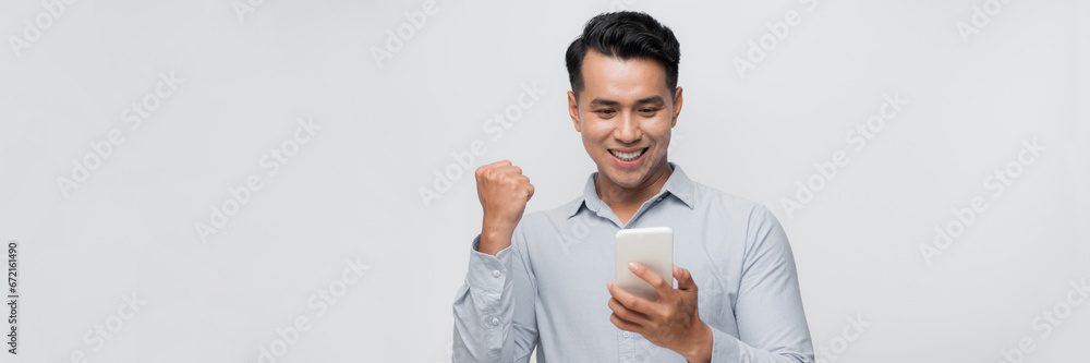 Excited asian millennial man isolated on white background look at smartphone happy get good text message Excited asian millennial man isolated on white background look at smartphone happy get good text message