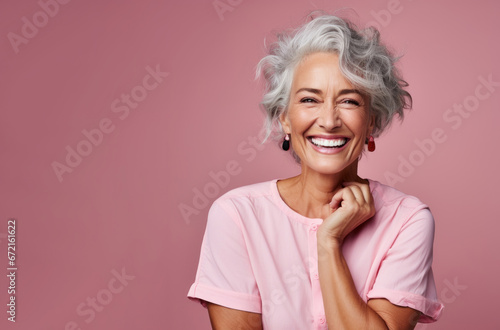 Beautiful happy elderly mature well-groomed woman model 50, 60, 70 years old posing on a pink background