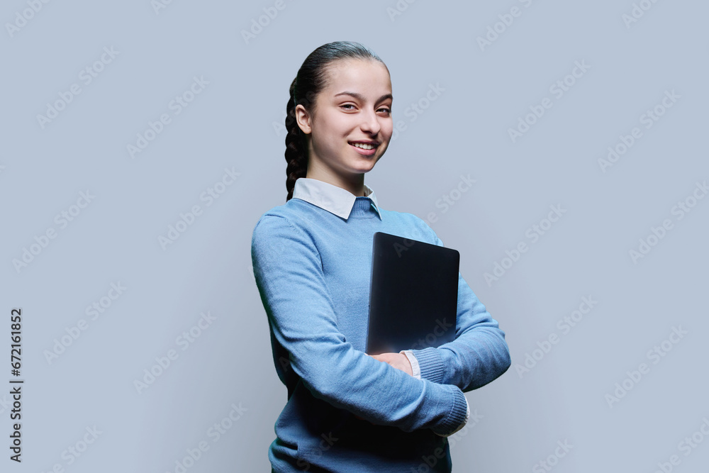 Portrait of teenage high school student girl with laptop in hands on grey background Portrait of teenage high school student girl with laptop in hands on grey background