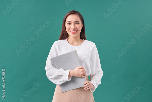 Portrait of a happy asian businesswoman holding clipboard isolated over green background © makistock