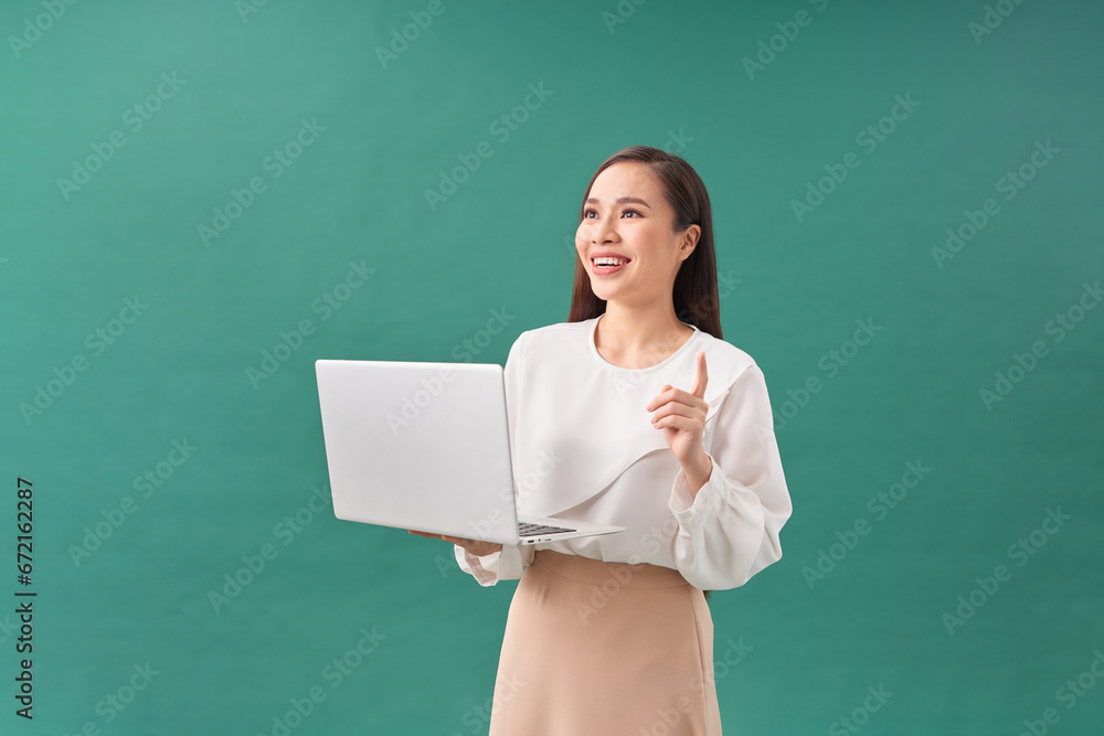 Portrait of a happy asian businesswoman working on laptop computer isolated over green background Portrait of a happy asian businesswoman working on laptop computer isolated over green background