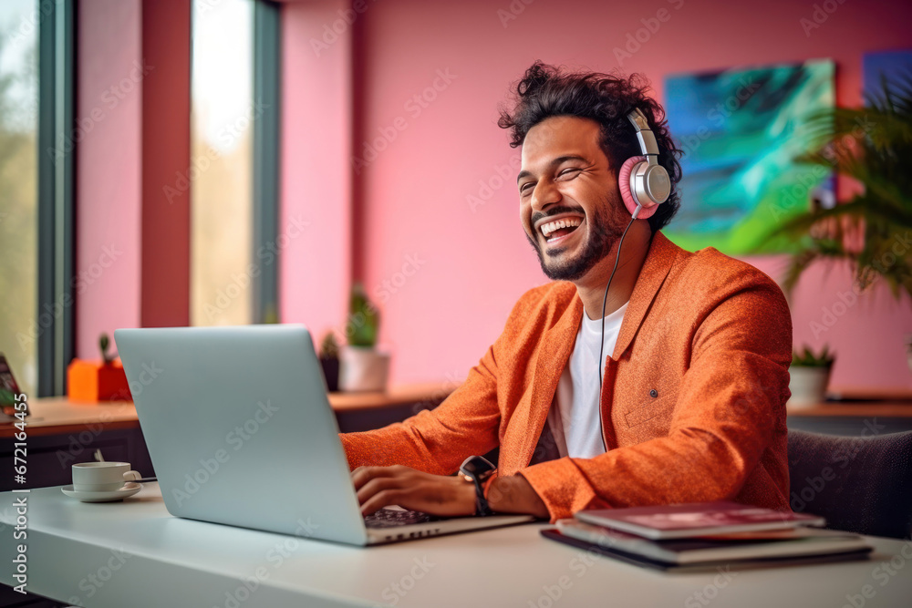 Cheerful indian man in orange jacket working on laptop Cheerful indian man in orange jacket working on laptop