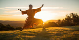 shaolin monk practicing kung fu outside on the grass at sunset 