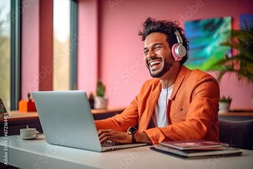 Cheerful indian man in orange jacket working on laptop