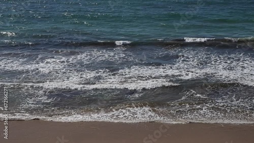 Ondas do mar rebentando calmamente na areia da praia. Mar calmo com ondas pequenas. Oceano azul numa praia deserta. photo
