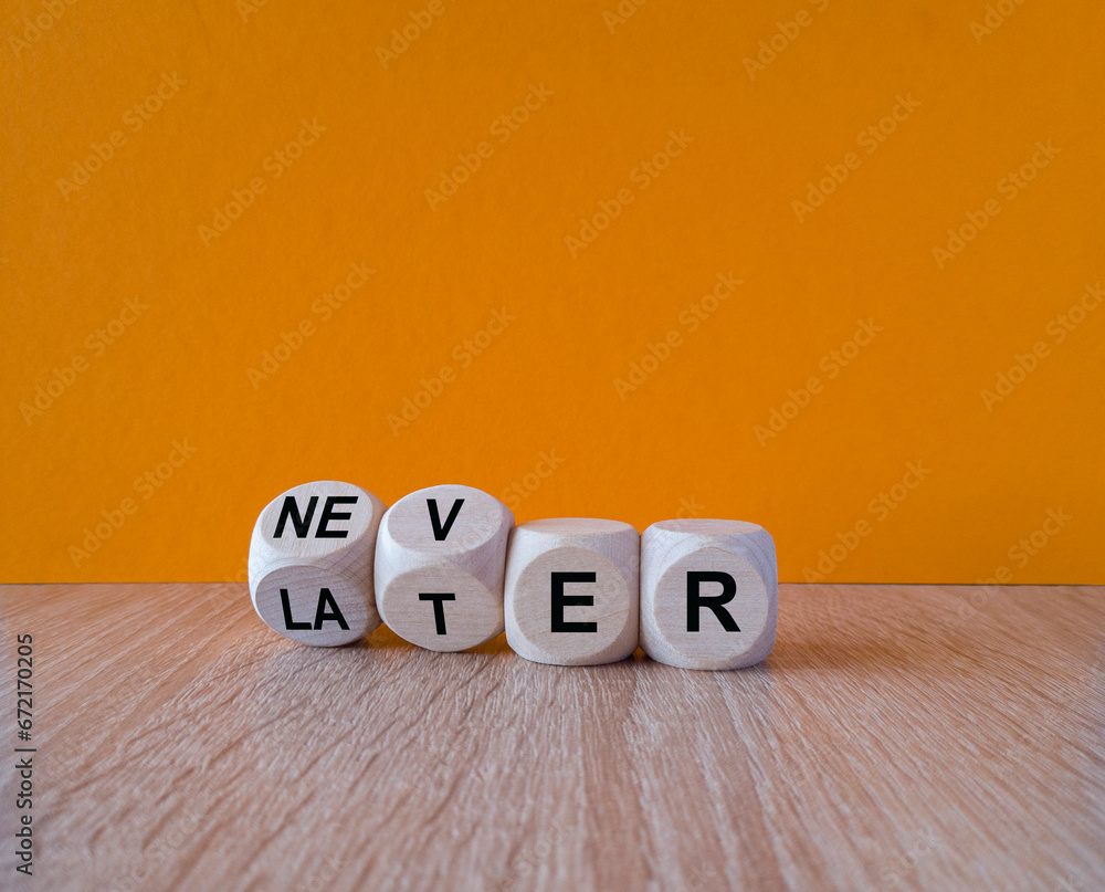 From later to never symbol. Turned a cube and changes the word later to never. Beautiful wooden table, orange background. Business and later to never concept.