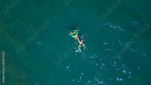 Mom and daughter swim in the sea, top view. Summer vacation and vacation concept