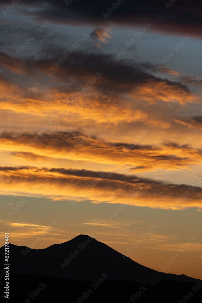 Stunning sunrise with beautiful shades of orange, pink, purple and blue colors with the silhouette of a mountain range. Wallpaper, natural background with copy space.
