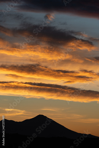 Obraz na płótnie Stunning sunrise with beautiful shades of orange, pink, purple and blue colors with the silhouette of a mountain range. Wallpaper, natural background with copy space. w salonie