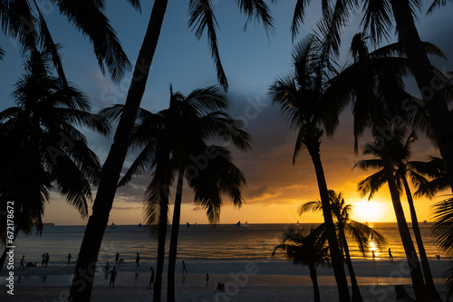 Obraz na płótnie (Selective focus) Stunning view of a dramatic sunset in the background and the silhouette of coconut palm trees in the foreground. White Beach, Boracay Island, Philippines. w salonie